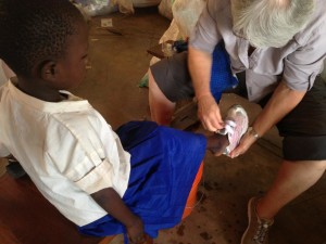 Elaine fitting shoes onto the feet of a young girl in Tanzania